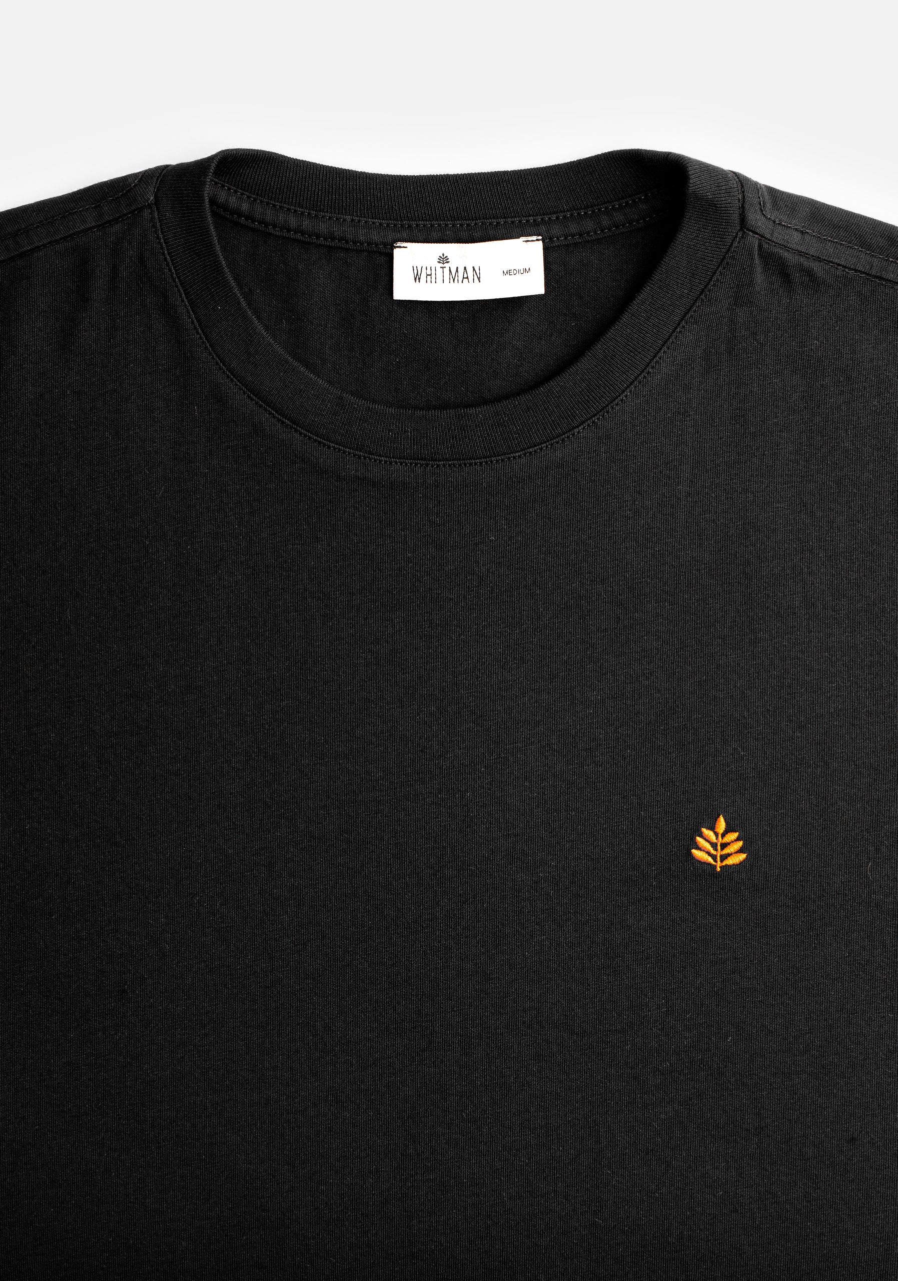 Detalle de cuello redondo en camiseta negra Whitman